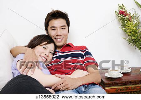 Portrait of a mid adult man lying on a couch with a young woman and smiling View Large Photo Image Stock Image - Portrait of a mid adult man lying on a couch with a young woman and smiling. Fotosearch