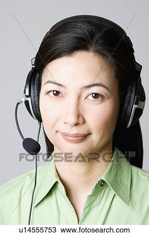 Stock Image - Portrait of a mid adult woman with a headset on her ear. Fotosearch