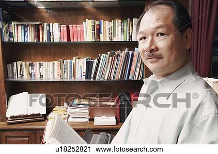 Stock Image - Portrait of a senior man holding a book. Fotosearch
