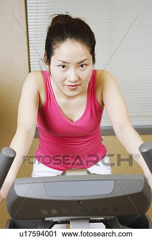 Stock Image - Portrait of a teenage girl exercising on an exercise bike. Fotosearch