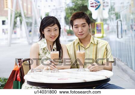 Stock Image - Portrait of a young couple sitting in a cafeteria. Fotosearch