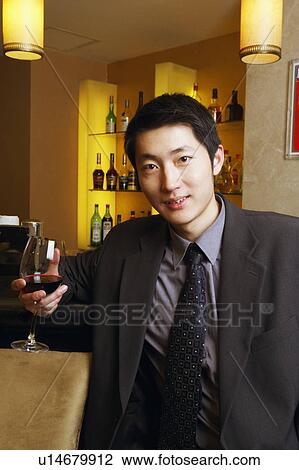 Stock Image - Portrait of a young man holding a glass of red wine. Fotosearch