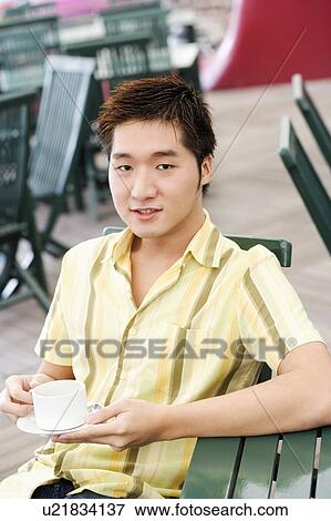 Portrait of a young man holding a coffee cup and a saucer View Large Photo Image Stock Photo - Portrait of a young man holding a coffee cup and a saucer. Fotosearch