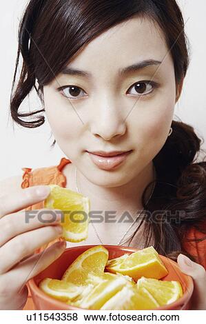 Portrait of a young woman eating slices of orange View Large Photo Image Stock Photo - Portrait of a young woman eating slices of orange. Fotosearch