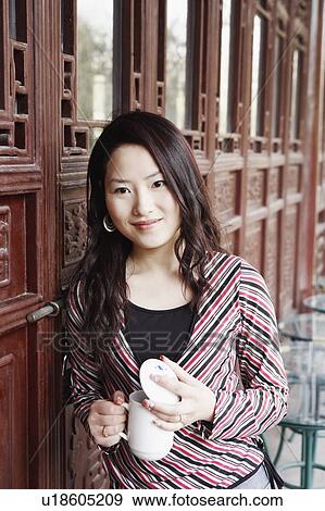 Portrait of a young woman holding a mug with a lid smiling View Large Photo Image Stock Photo - Portrait of a young woman holding a mug with a lid smiling. Fotosearch