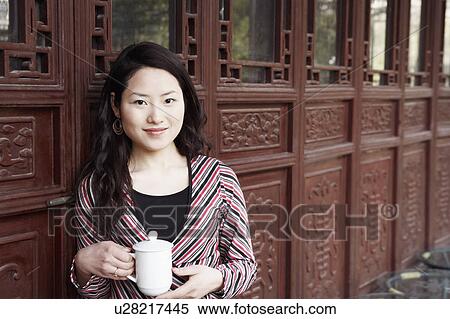 Portrait of a young woman holding a mug with a lid smiling View Large Photo Image Stock Photography - Portrait of a young woman holding a mug with a lid smiling. Fotosearch