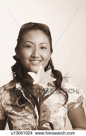 Portrait of a young woman holding a flower and smiling View Large Photo Image Picture - Portrait of a young woman holding a flower and smiling. Fotosearch