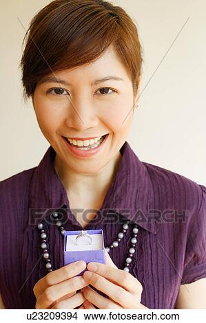 Portrait of a young woman holding a ring and smiling View Large Photo Image Picture - Portrait of a young woman holding a ring and smiling. Fotosearch
