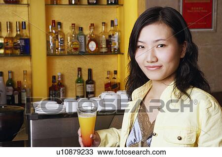 Stock Image - Portrait of a young woman holding a glass. Fotosearch