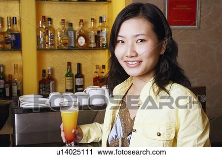 Stock Image - Portrait of a young woman holding a glass. Fotosearch
