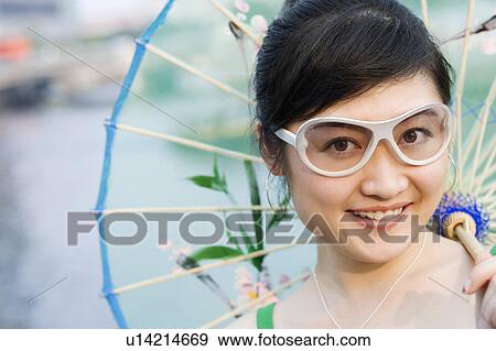 Portrait of a young woman holding a parasol and smiling View Large Photo Image Stock Photo - Portrait of a young woman holding a parasol and smiling. Fotosearch