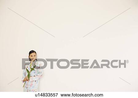 Stock Photo - Portrait of a young woman holding a flower. Fotosearch