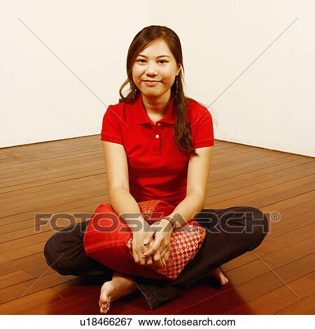 Portrait of a young woman holding a cushion on the floor and posing View Large Photo Image Stock Photo - Portrait of a young woman holding a cushion on the floor and posing. Fotosearch