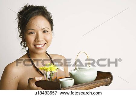 Stock Photo - Portrait of a young woman holding a serving tray and smiling. Fotosearch
