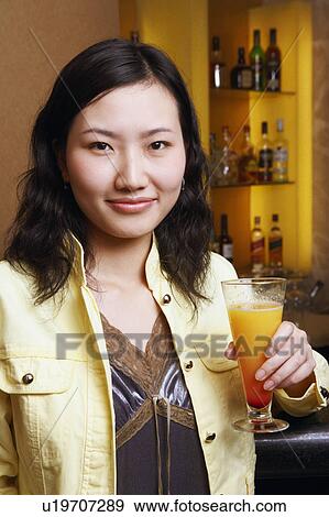 Stock Photo - Portrait of a young woman holding a glass. Fotosearch