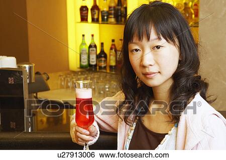 Portrait of a young woman holding a glass View Large Photo Image Stock Photograph - Portrait of a young woman holding a glass. Fotosearch
