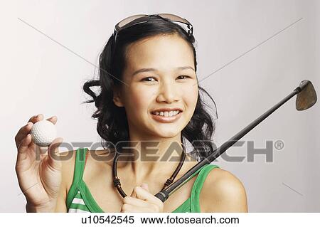 Stock Photography - Portrait of a young woman holding a golf club and a golf ball. Fotosearch