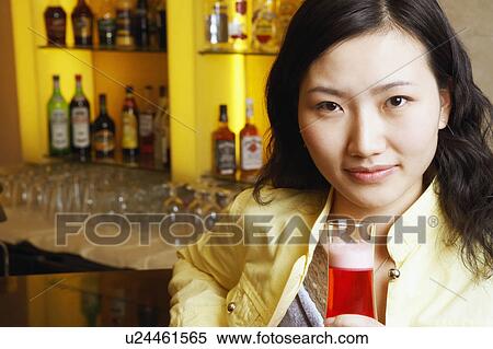 Stock Photography - Portrait of a young woman holding a glass. Fotosearch