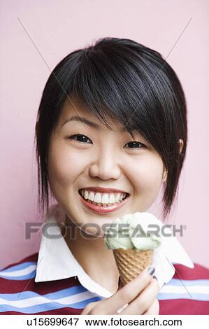 Stock Photo - Portrait of a young woman holding an ice-cream cone. Fotosearch
