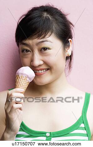 Stock Photo - Portrait of a young woman holding an ice-cream cone. Fotosearch