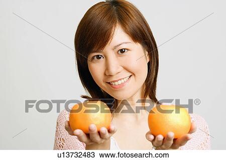 Portrait of a young woman holding oranges View Large Photo Image Stock Image - Portrait of a young woman holding oranges. Fotosearch