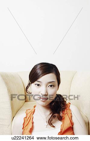 Picture - Portrait of a young woman leaning against an armchair. Fotosearch