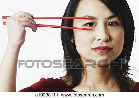 Portrait of a young woman looking through chopsticks View Large Photo Image Stock Image - Portrait of a young woman looking through chopsticks. Fotosearch