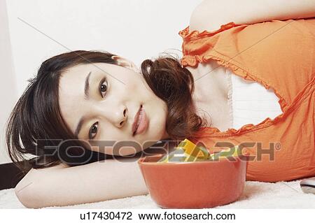 Stock Image - Portrait of a young woman lying down. Fotosearch