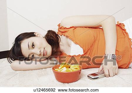 Portrait of a young woman lying on her side holding a mobile phone View Large Photo Image Stock Image - Portrait of a young woman lying on her side holding a mobile phone. Fotosearch