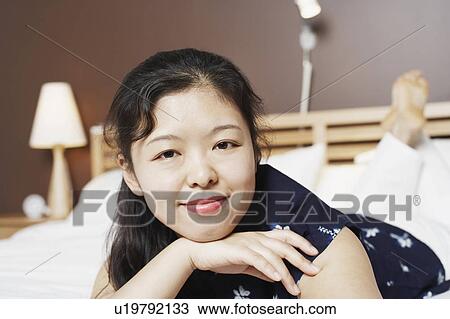 Portrait of a young woman lying on the bed smiling View Large Photo Image Stock Image - Portrait of a young woman lying on the bed smiling. Fotosearch