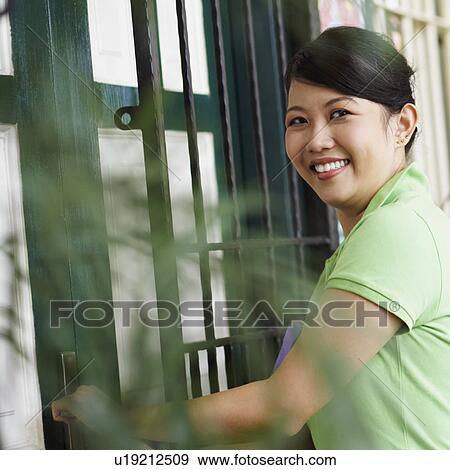 Portrait of a young woman opening a door with a young man standing beside her View Large Photo Image Stock Photo - Portrait of a young woman opening a door with a young man standing beside her. Fotosearch