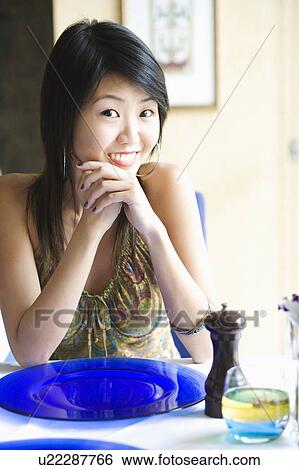 Portrait of a young woman sitting in a restaurant with her hands clasped View Large Photo Image Stock Photograph - Portrait of a young woman sitting in a restaurant with her hands clasped. Fotosearch