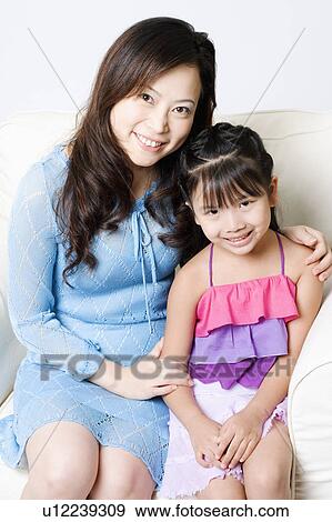 Portrait of a young woman sitting in an armchair with her daughter View Large Photo Image Stock Photo - Portrait of a young woman sitting in an armchair with her daughter. Fotosearch