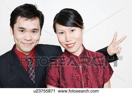 Portrait of a young woman smiling and a mid adult man making a peace sign View Large Photo Image Stock Image - Portrait of a young woman smiling and a mid adult man making a peace sign. Fotosearch