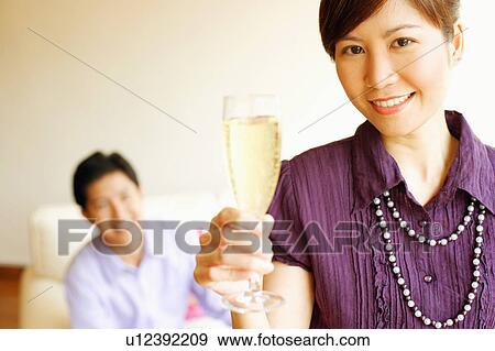 Stock Photo - Portrait of a young woman smiling and holding a champagne flute. Fotosearch