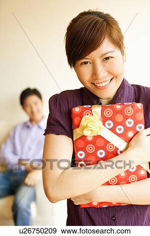 Portrait of a young woman smiling and holding a gift View Large Photo Image Stock Photo - Portrait of a young woman smiling and holding a gift. Fotosearch