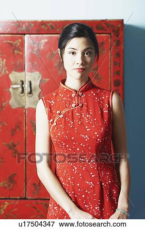 Stock Photo - Portrait of a young woman standing in front of a cupboard. Fotosearch