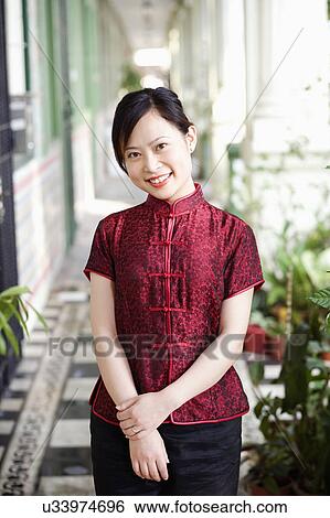 Stock Photograph - Portrait of a young woman standing in corridor and smiling. Fotosearch