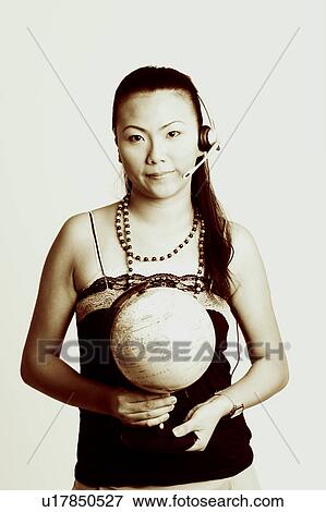 Stock Photo - Portrait of a young woman wearing a headset and holding a globe. Fotosearch