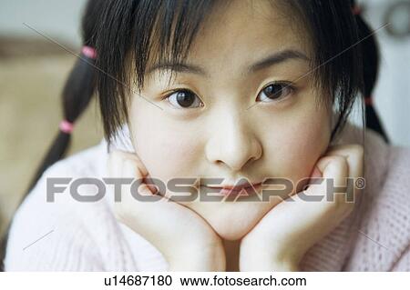 Stock Image - Portrait of a young woman with her hand on her chin. Fotosearch