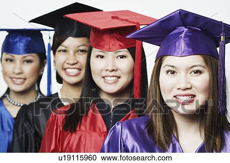 Stock Image - Portrait of four female graduates standing in a row. Fotosearch