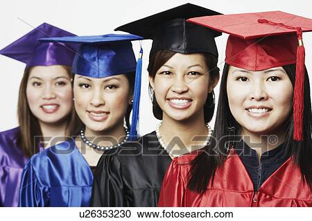 Stock Image - Portrait of four female graduates standing in a row. Fotosearch