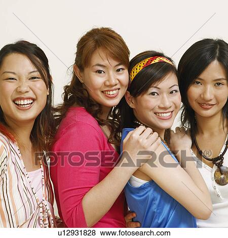 Stock Photo - Portrait of four young women hugging each other and posing. Fotosearch