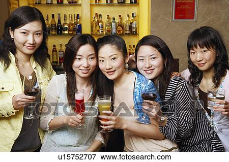 Stock Photo - Portrait of three teenage girls and two young women holding drinks. Fotosearch