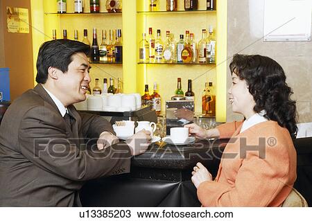 Side profile of a businessman and a businesswoman sitting at a bar counter View Large Photo Image Stock Image - Side profile of a businessman and a businesswoman sitting at a bar counter. Fotosearch