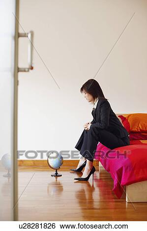 Side profile of a businesswoman sitting on the bed and looking at a globe View Large Photo Image Stock Photograph - Side profile of a businesswoman sitting on the bed and looking at a globe. Fotosearch