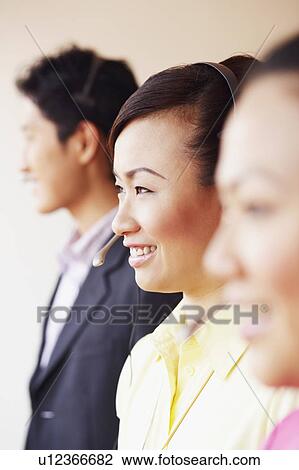 Side profile of a female customer service representative smiling with two colleagues View Large Photo Image Stock Image - Side profile of a female customer service representative smiling with two colleagues. Fotosearch