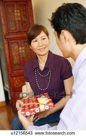 Side profile of a young man giving a gift to a young woman View Large Photo Image Stock Image - Side profile of a young man giving a gift to a young woman. Fotosearch