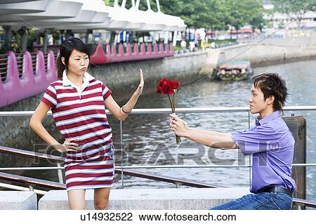 Stock Image - Side profile of a young man proposing a young woman. Fotosearch
