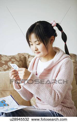 Stock Image - Side profile of a young woman doing embroidery. Fotosearch